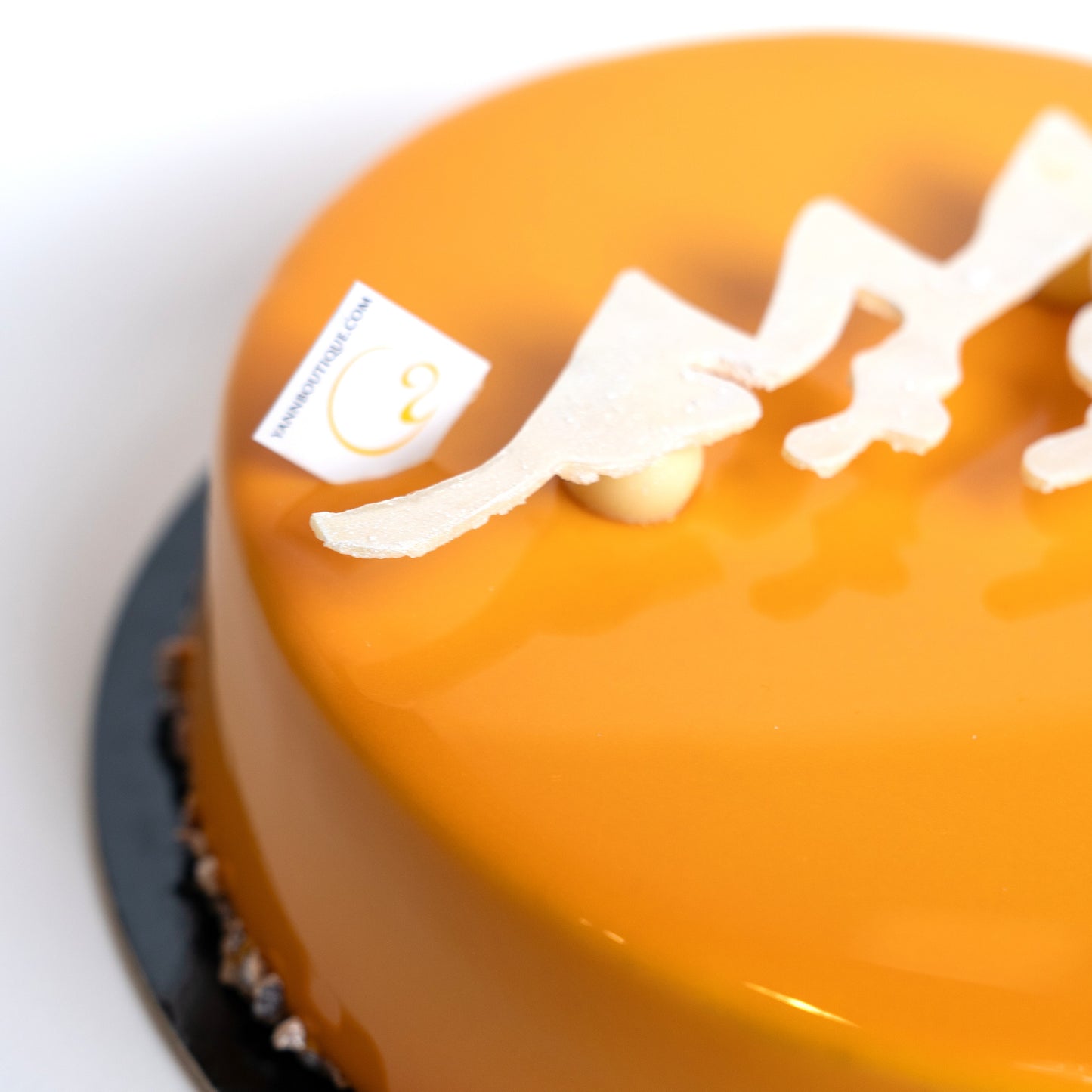 Close-up of an orange cake with white decorative chocolate elements on a white background