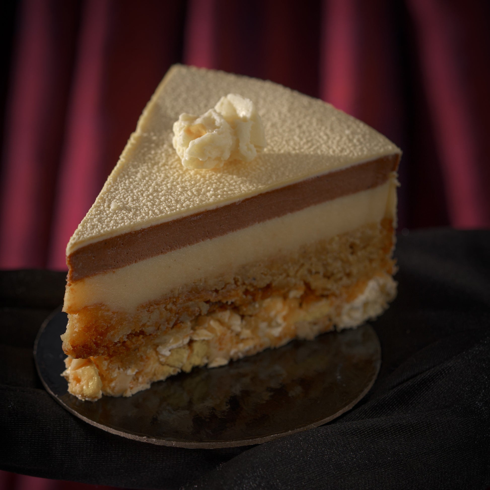 A slice of gourmet Father's Day dessert in Calgary inspired by popcorn and movie nights, combining chocolate bavaroise, corn blondie, corn crunch, and white chocolate velvet finish.