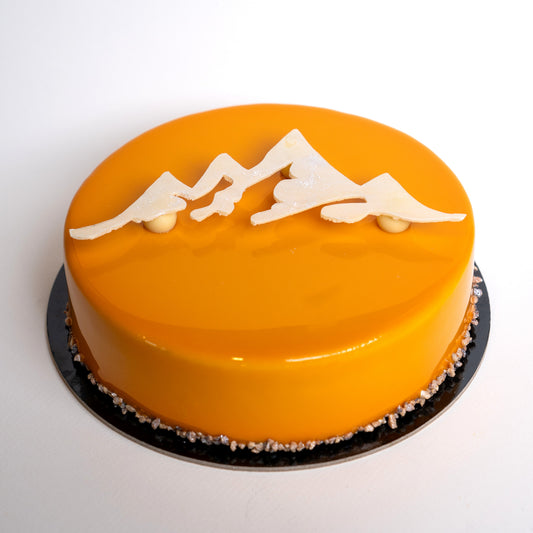 Round orange cake with mountain designs on a white background