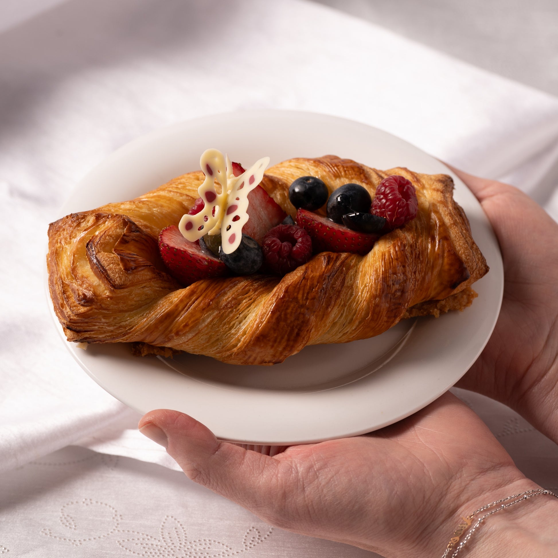 Seasonal fruit croissant plated and ready to serve, Calgary bakery dessert with strawberries and blueberries, Easter pastries YYC, Yann Haute Patisserie handcrafted croissant, elegant fruit dessert Calgary, local artisan bakery Canada