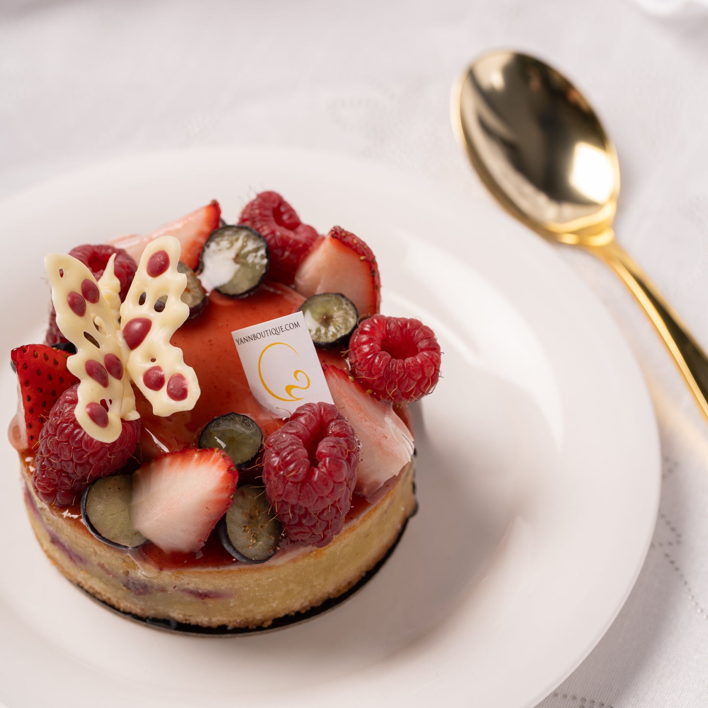 Fresh strawberries and raspberries on coconut crème brûlée tart, Coeur de Coco Mother’s Day cake Calgary, elegant fruit tart presentation, artisan French pastry by Yann Haute Patisserie, seasonal dessert YYC