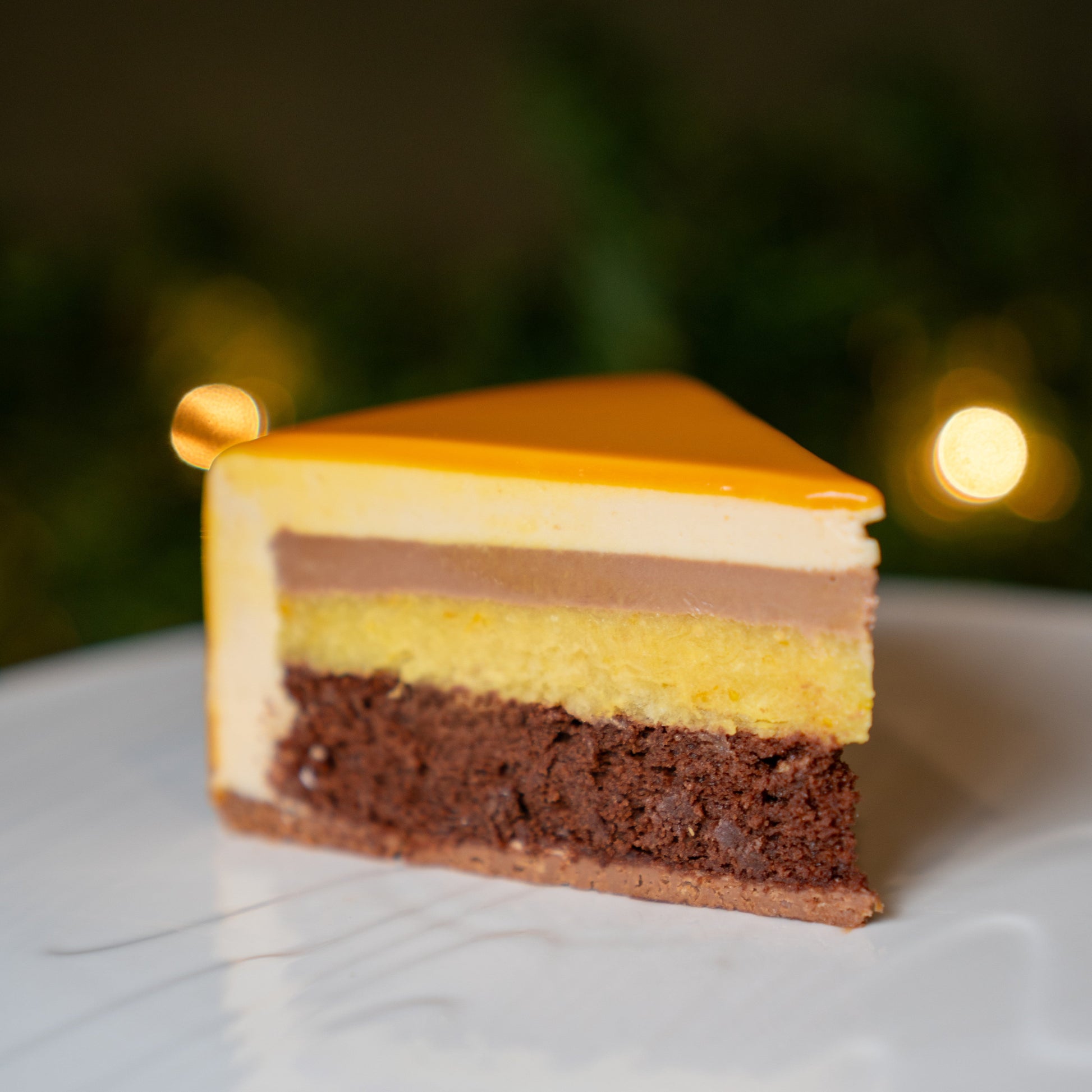 Layered 3 sisters dessert slice on a white plate with a blurred background