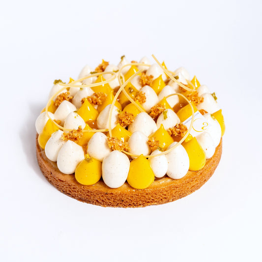 Sable Breton base, white chocolate &amp; coconut crunch, passion fruit compote, white chocolate &amp; vanilla bean chantilly, mango cremeux, coconut nougatine, candied lime zests, passion fruit chocolate swirls.