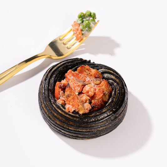 Homemade squid ink croissant filled with fish velouté, green peas and seaweed, topped with wild Canadian teriyaki salmon and sesame seeds.