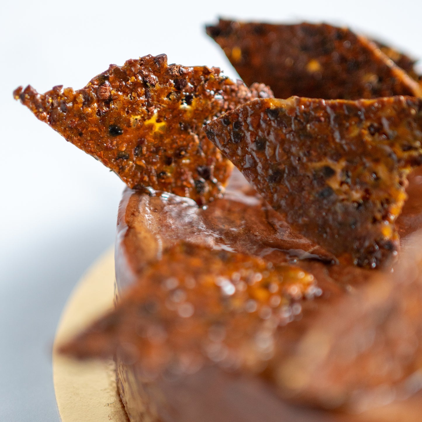 Close-up of chocolate flan with cocoa nibs nougatine on a white background
