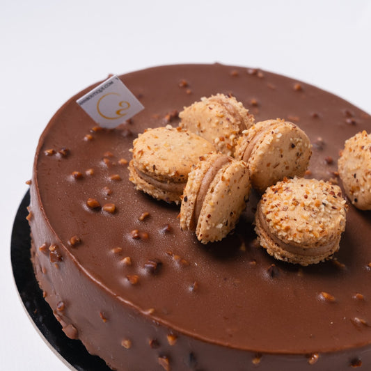 A center of hazelnut praline with hazelnut cream in a choux (cream puff) coated in chocolate with a macaron on top!Yann Haute Patisserie, French dessert boutique for the best authentic French pastry shop in in Calgary. Croissants, cakes, desserts, croissants & macarons!