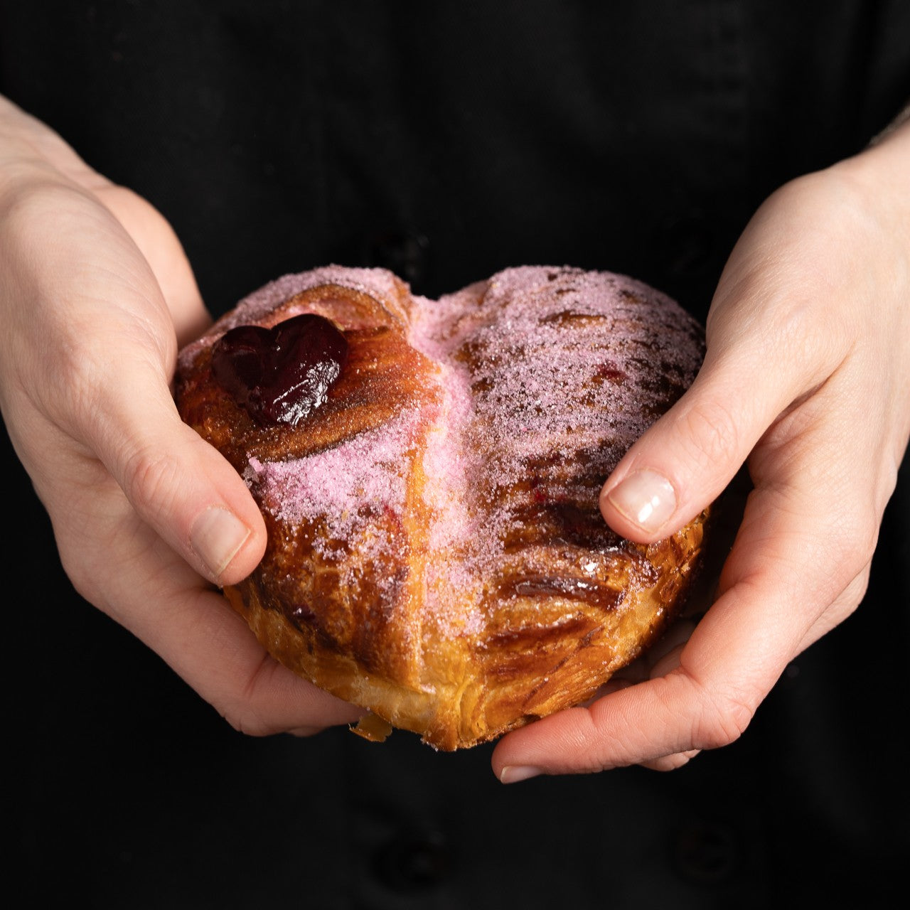Heart-shaped buttery croissant filled with red berry compote, dusted with pink sugar and finished with a piped berry heart.